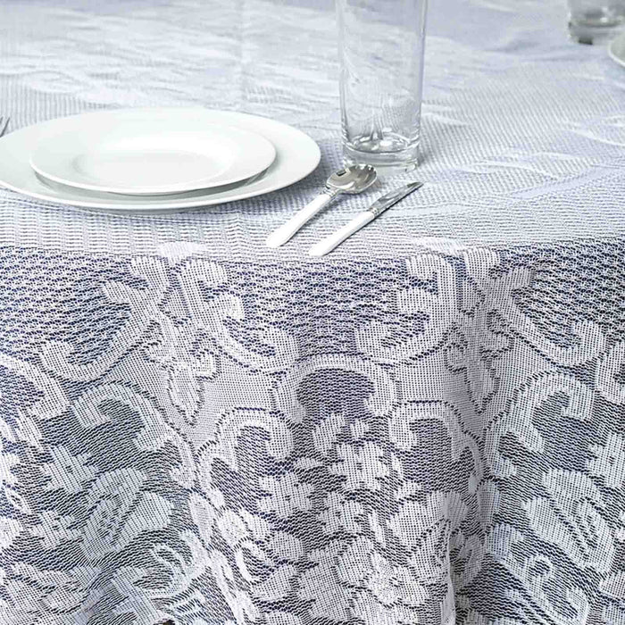 Elegant lace tablecloth on a dining table with plates and glassware.