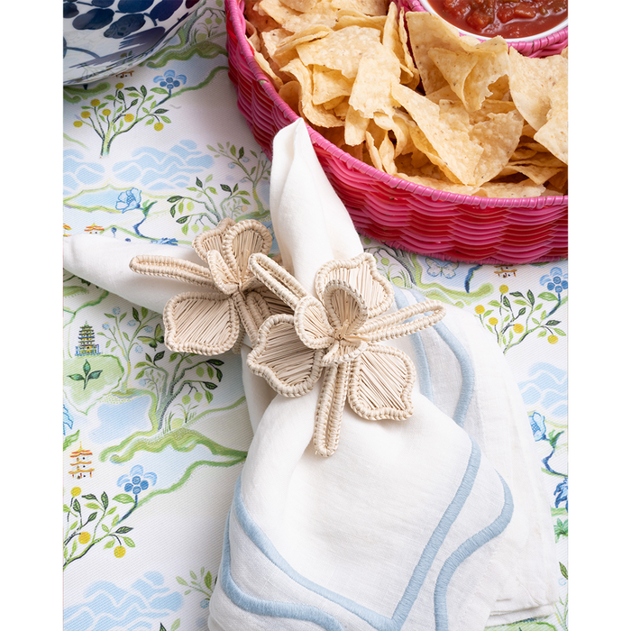 white napkin with flower shaped napkin ring on a blue patterned tablecloth