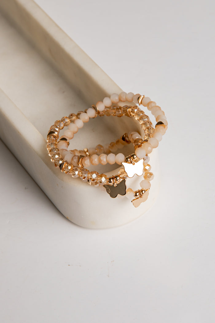 Stack of gold and pearl beaded rings on a white surface