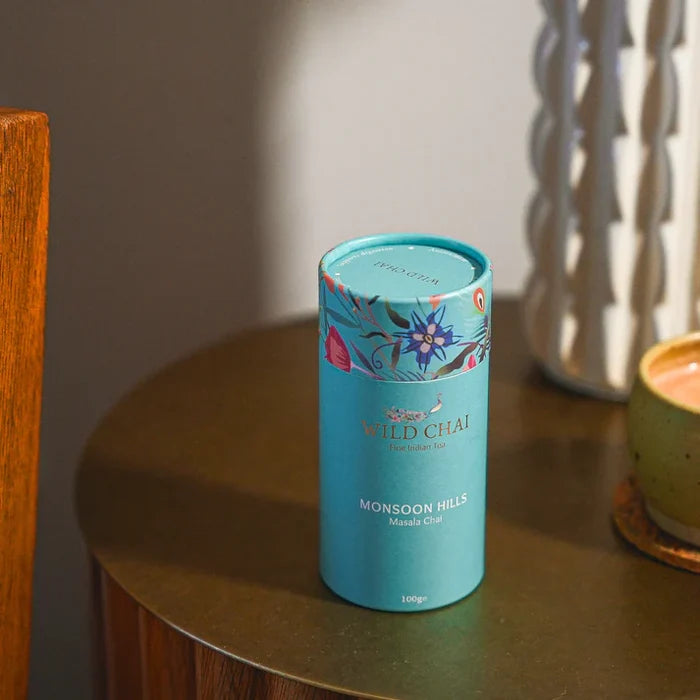 Blue cylindrical tea canister with floral design on a wooden surface
