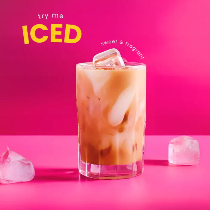 Glass of iced coffee with ice cubes on a pink background, text 'try me ICED sweet & fragrant'.