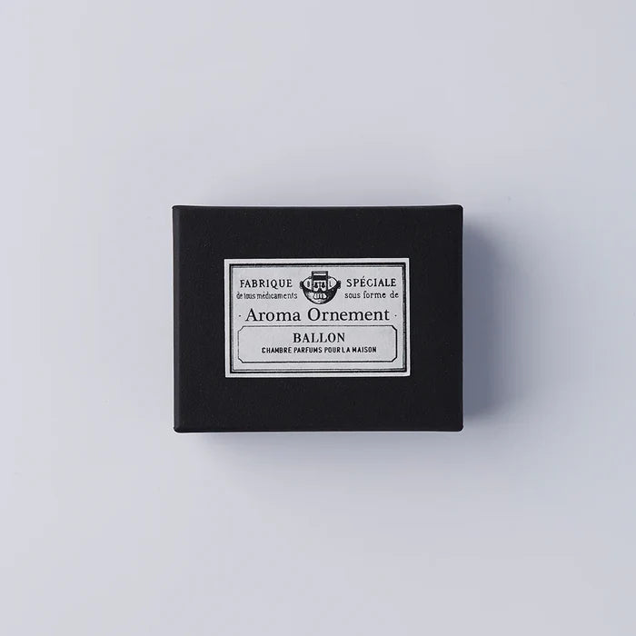 Black Aroma Ornament box with vintage-style French label design, photographed against a clean white background in a minimalist product presentation.