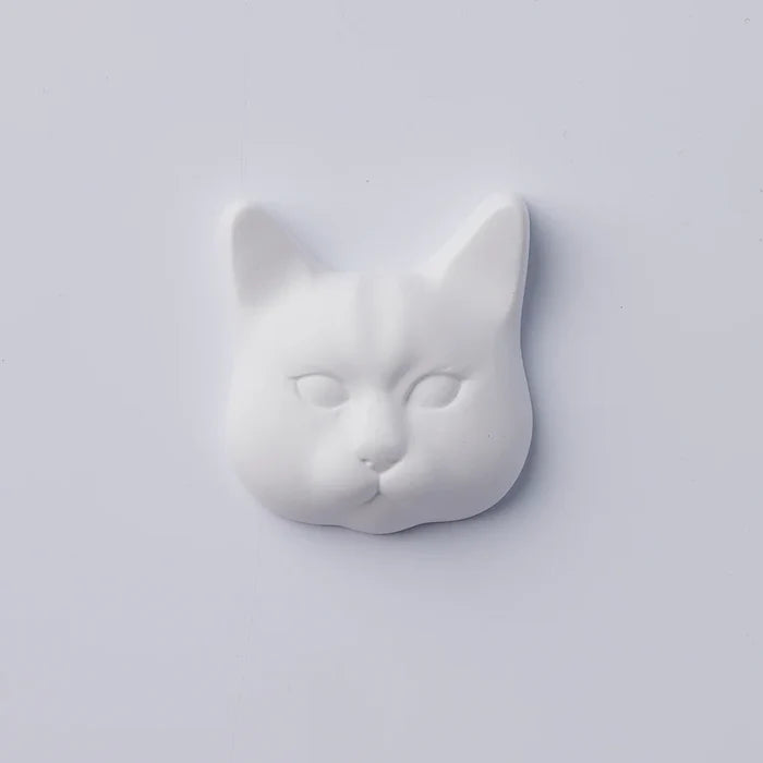 White cat-face decorative object with sculpted features and minimalist design, photographed against a clean white background in a modern product presentation.