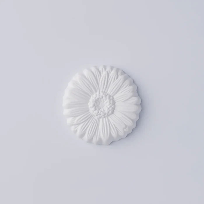 White daisy-shaped decorative object with detailed sculpted petals and textured center, photographed against a clean white background in a minimalist product presentation.