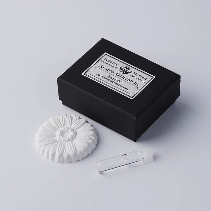White daisy-shaped aroma ornament set with a black vintage-style gift box and small fragrance vial, displayed on a clean white background in a minimalist product presentation.