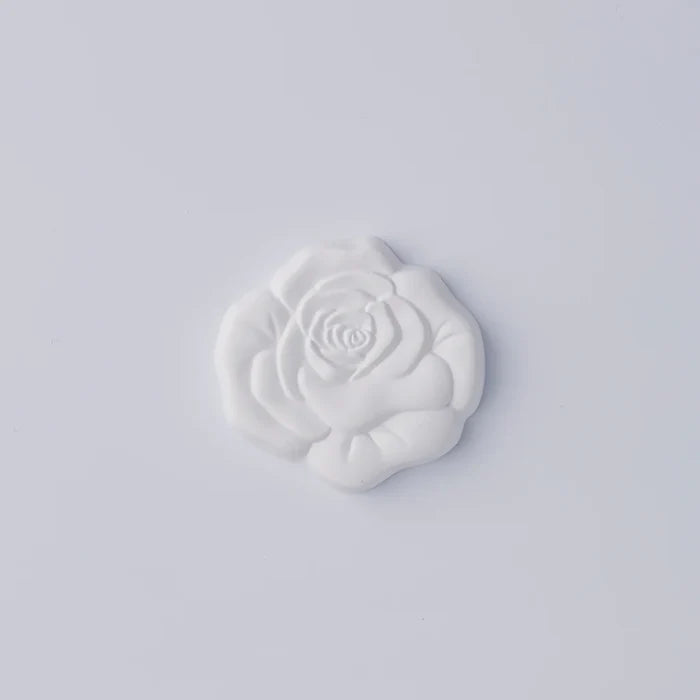 White rose-shaped decorative object with sculpted petals, photographed against a clean white background in a minimalist product presentation.