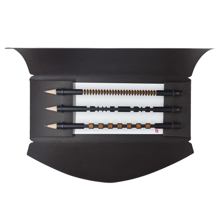 Set of three minimalist black pencils with decorative grip patterns and wooden accents presented in an elegant gift box, modern designer stationery set for writing and sketching.