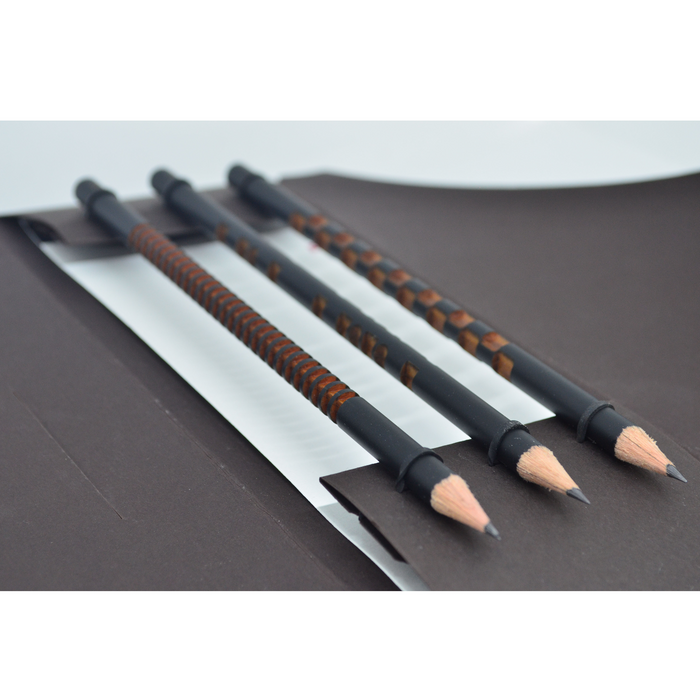 Three minimalist black designer pencils with carved wooden grip patterns displayed in a premium stationery case, modern luxury pencils for writing, sketching, and drawing.