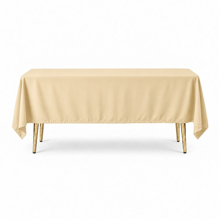60"x102" A rectangular table covered with a plain beige tablecloth, shown against a clean white background. The table has slim metallic legs in a gold finish.