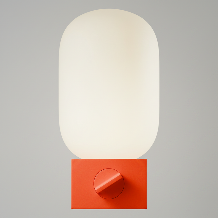 A modern wall lamp with a large, rounded, off-white translucent shade mounted on a bright orange-red square base featuring a circular control dial.