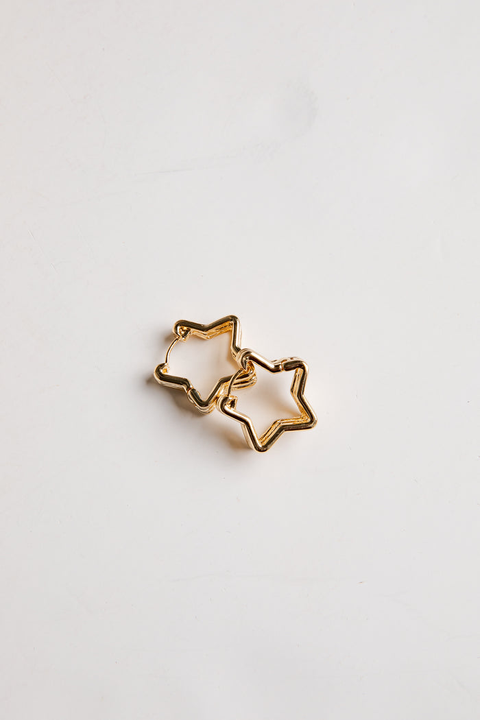 Gold star-shaped earrings on a light gray background