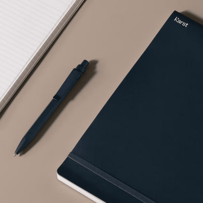 Dark blue pen and notebook on a beige surface