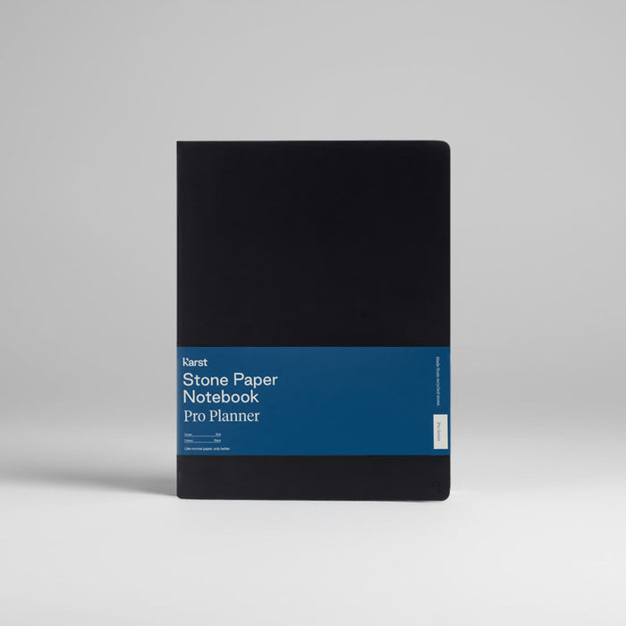 Black notebook with blue band featuring 'Karat Stone Paper Notebook Pro Planner' text on a gray background