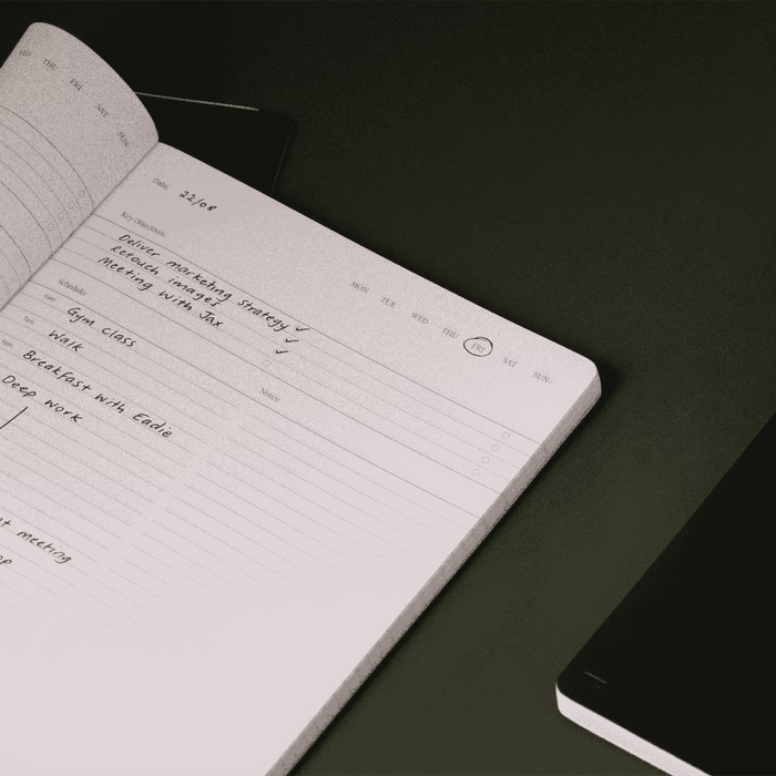 Open notebook with handwritten notes on a dark surface
