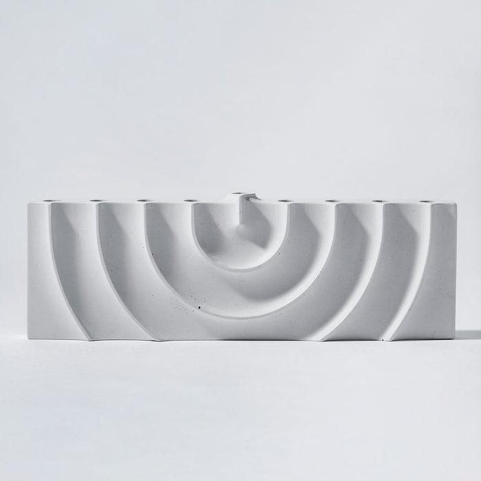 Logifaces, a geometric puzzle made of concrete triangular prisms, arranged in various configurations to form a continuous surface. The minimalist design encourages creative problem-solving and spatial thinking