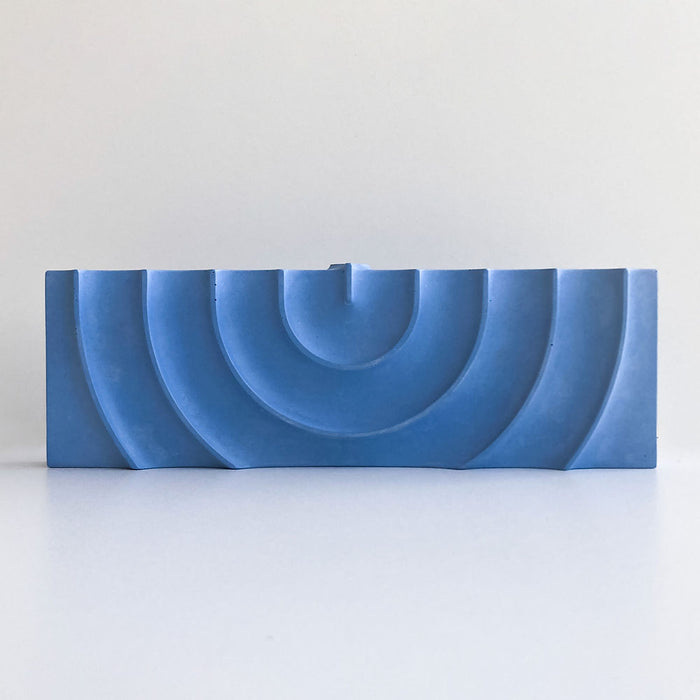 Logifaces, a geometric puzzle made of concrete triangular prisms, arranged in various configurations to form a continuous surface. The minimalist design encourages creative problem-solving and spatial thinking