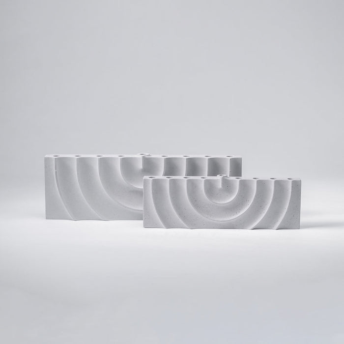 Logifaces, a geometric puzzle made of concrete triangular prisms, arranged in various configurations to form a continuous surface. The minimalist design encourages creative problem-solving and spatial thinking