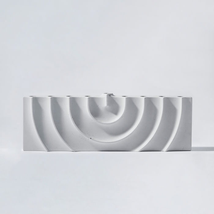 Logifaces, a geometric puzzle made of concrete triangular prisms, arranged in various configurations to form a continuous surface. The minimalist design encourages creative problem-solving and spatial thinking