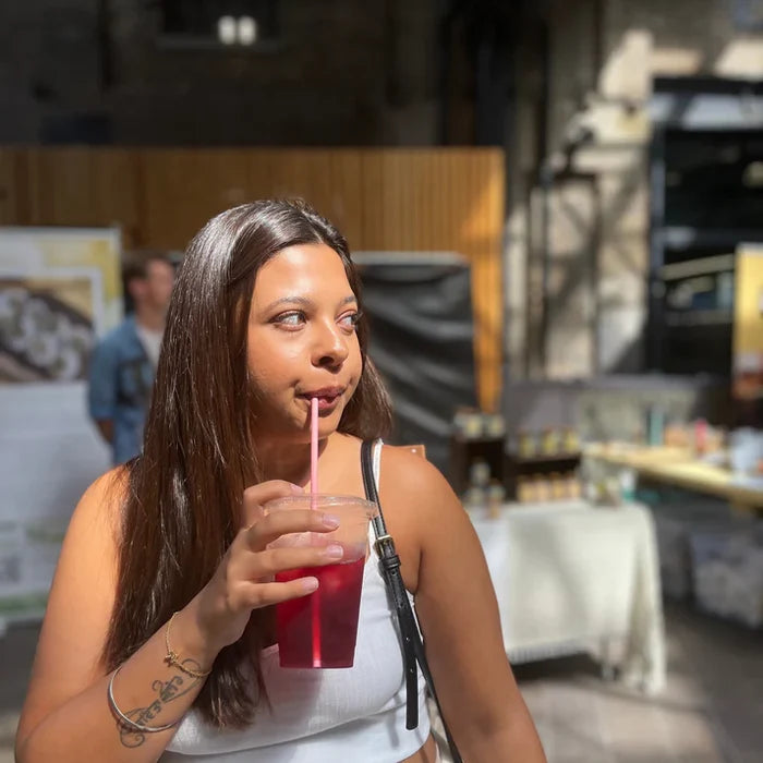 Woman drinking a red beverage with a straw in an indoor setting