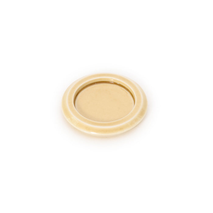 A single small round ceramic dish on a white background, finished in a smooth warm cream glaze with a gently raised rim.