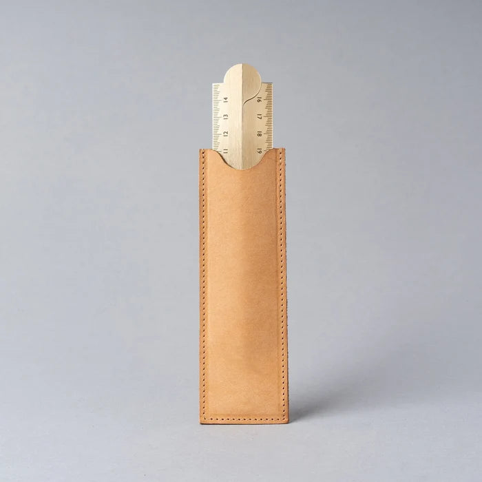 Leather pencil case with gold ruler on a gray background