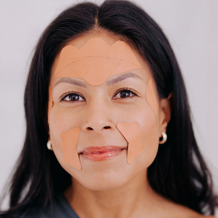 Frownies corners of eyes and mouth on a woman's face along with Frownies forehead and between the eyes facial patches