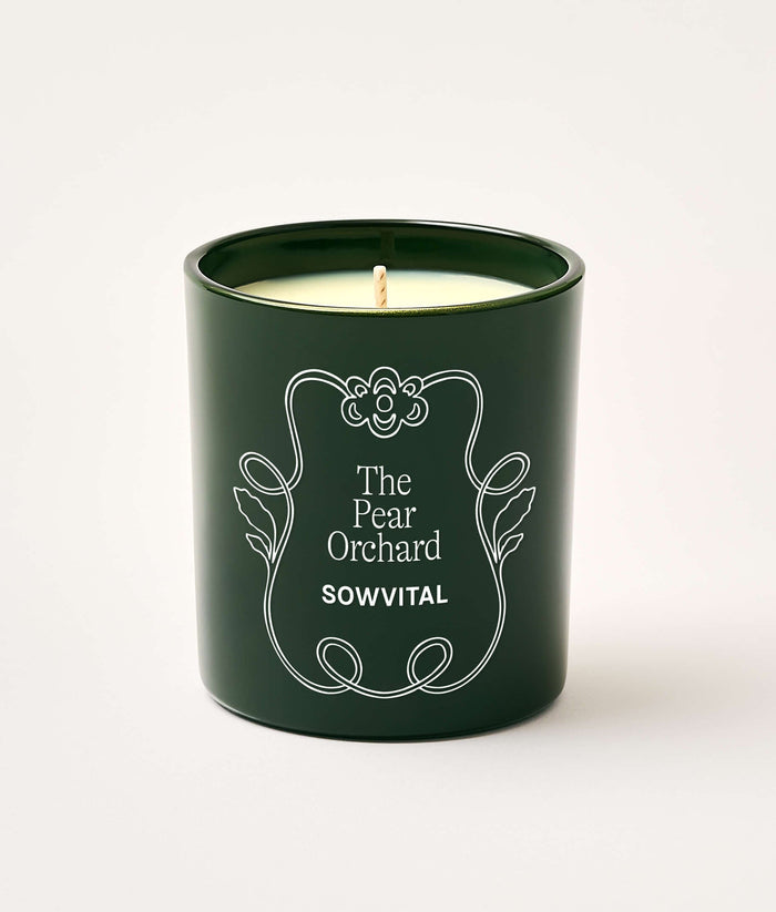 Green candle in a decorative container with 'The Pear Orchard' and 'Sowvital' text on a white background