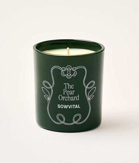 Green candle in a decorative container with 'The Pear Orchard' and 'Sowvital' text on a white background