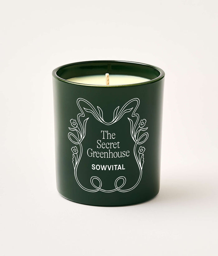 Green candle with 'The Secret Greenhouse' branding on a white background