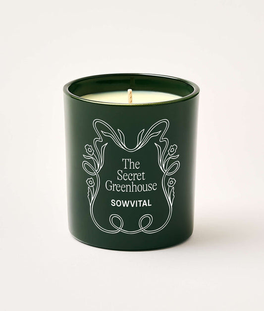 Green candle with 'The Secret Greenhouse' branding on a white background