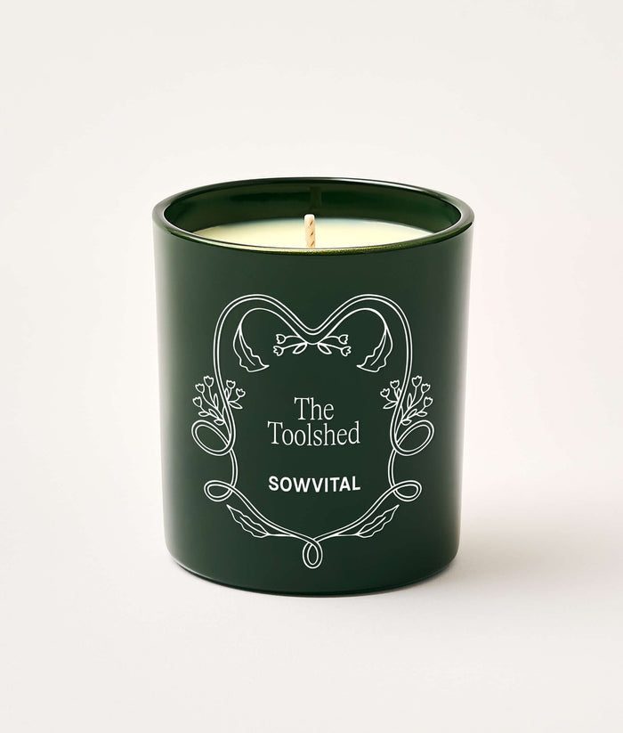 Green candle with decorative text on a white background