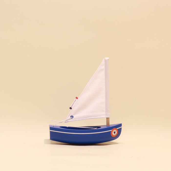 Model sailboat with a white sail on a beige background