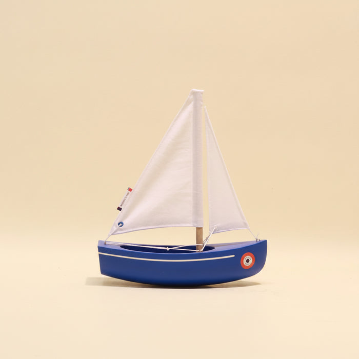Model sailboat with a white sail on a beige background