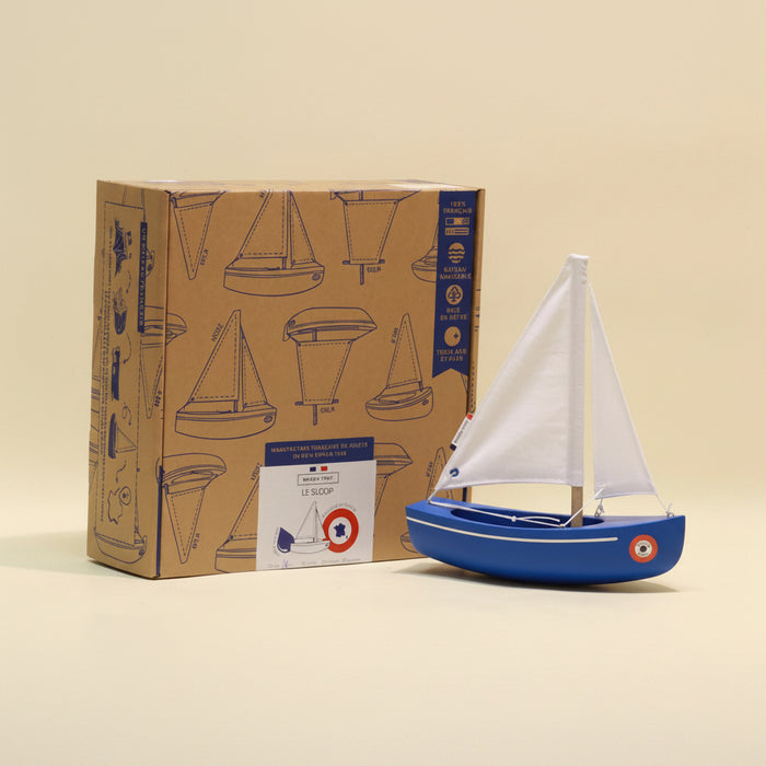 Model sailboat in front of its packaging box on a beige background
