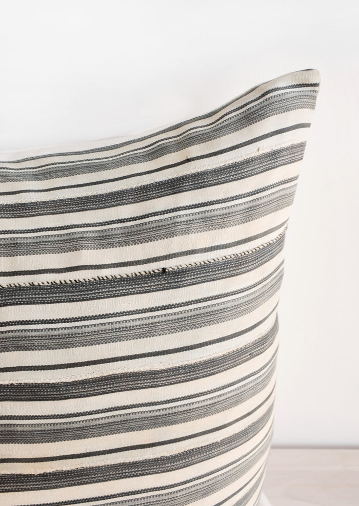 Close up of fabric on throw pillow in faded vintage fabric with allover tan and grey stripes