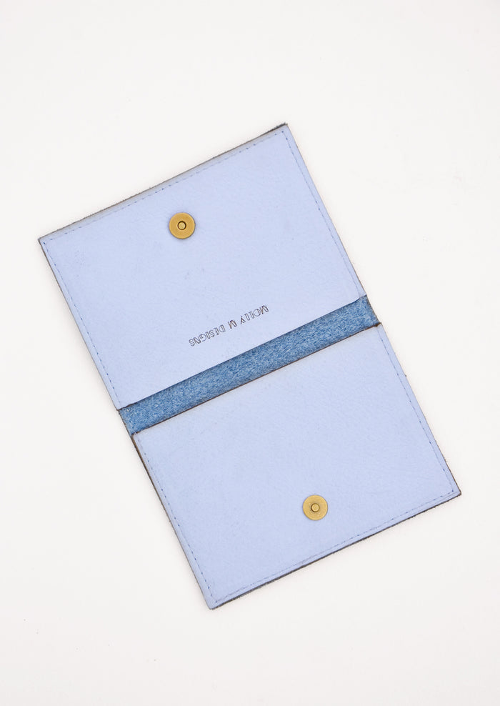 Slim blue leather wallet with two interior slip pockets that folds closed with a snap, shown open in