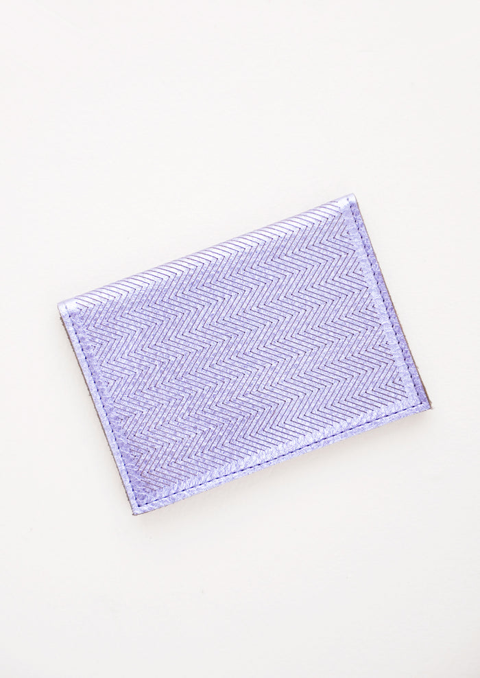 Slim metallic blue leather wallet with two interior slip pockets that folds closed with a snap, shown closed with zig zag etched pattern.